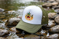 Green and white cap with a fish graphic on rocks by a water body